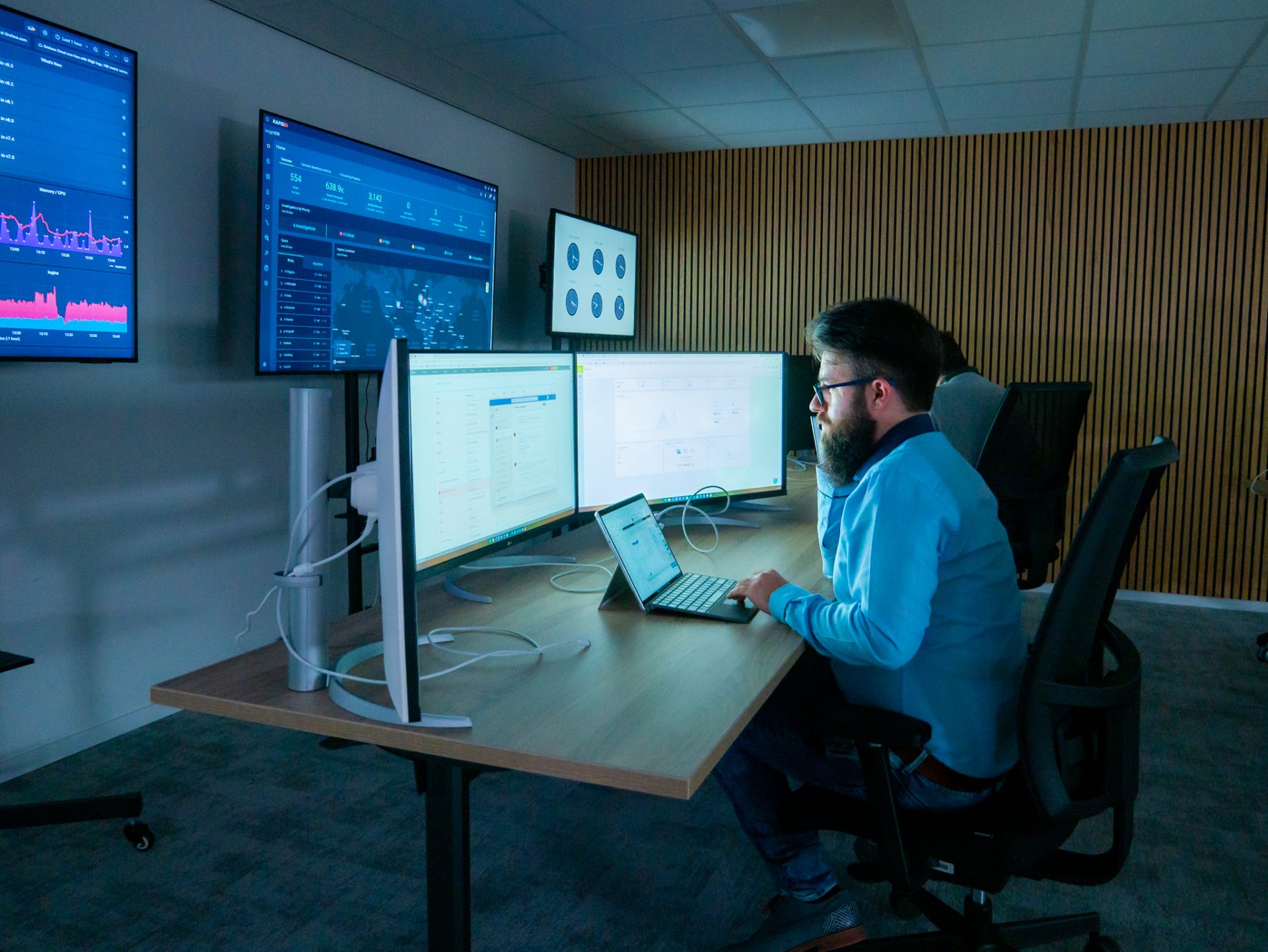An engineer making a phone call while sitting in front of his screens in the Security Operations Center